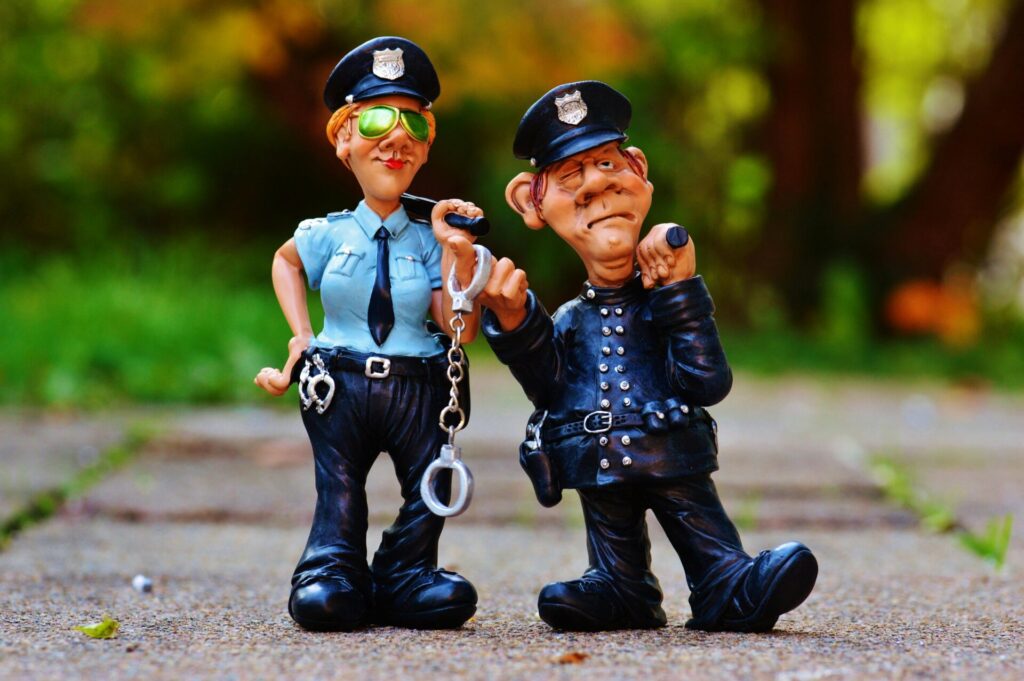 Two playful police figurines, complete with handcuffs and batons, depicted in a comical outdoor setting.