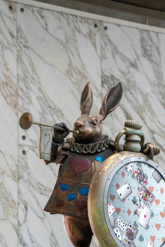 Whimsical rabbit sculpture inspired by Alice in Wonderland with a clock and playing cards theme.