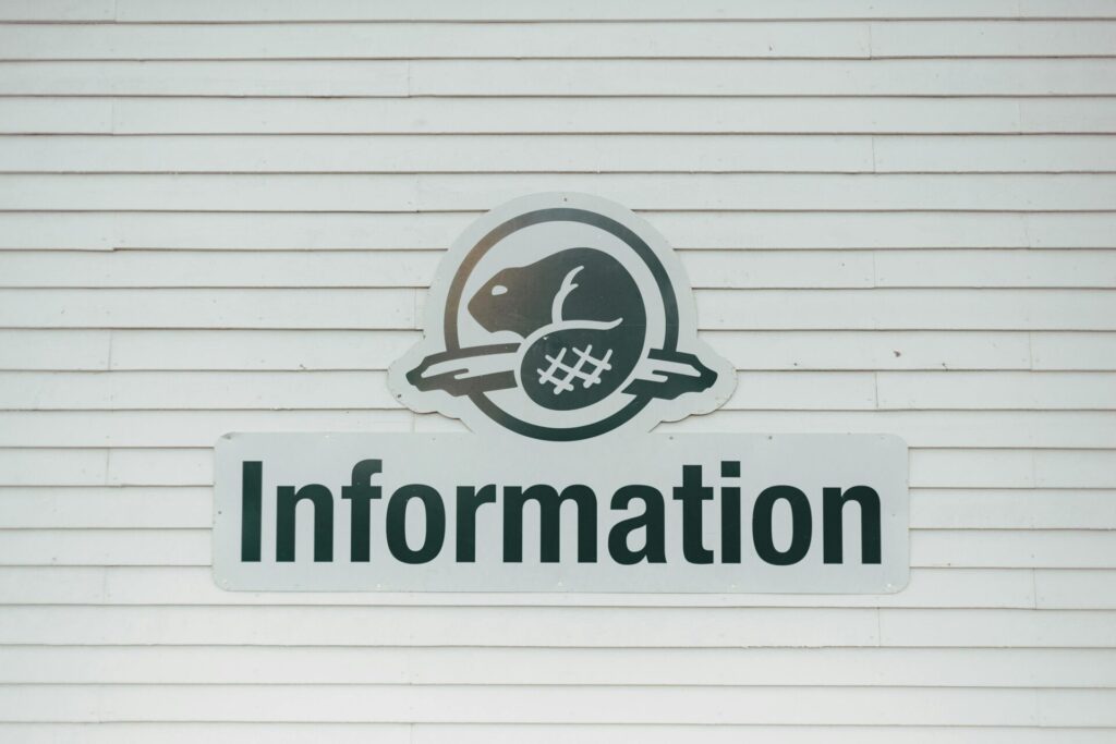 Close-up of an information sign on a textured white wall, featuring a beaver logo.