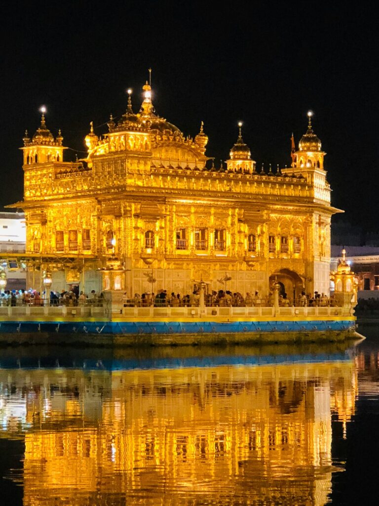 Breathtaking night view of the illuminated Golden Temple in Amritsar, India with reflection in water.