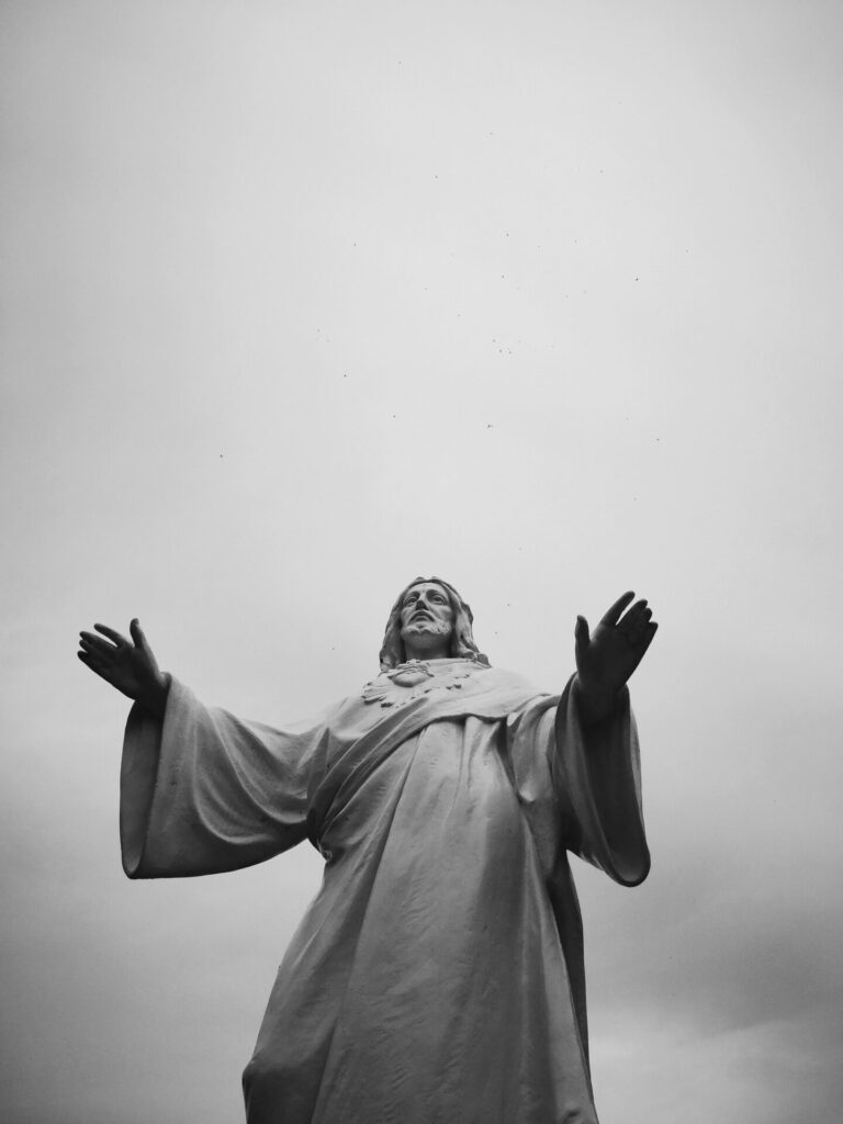Low angle view of a Jesus statue captured in monochrome, evokes spirituality and faith.